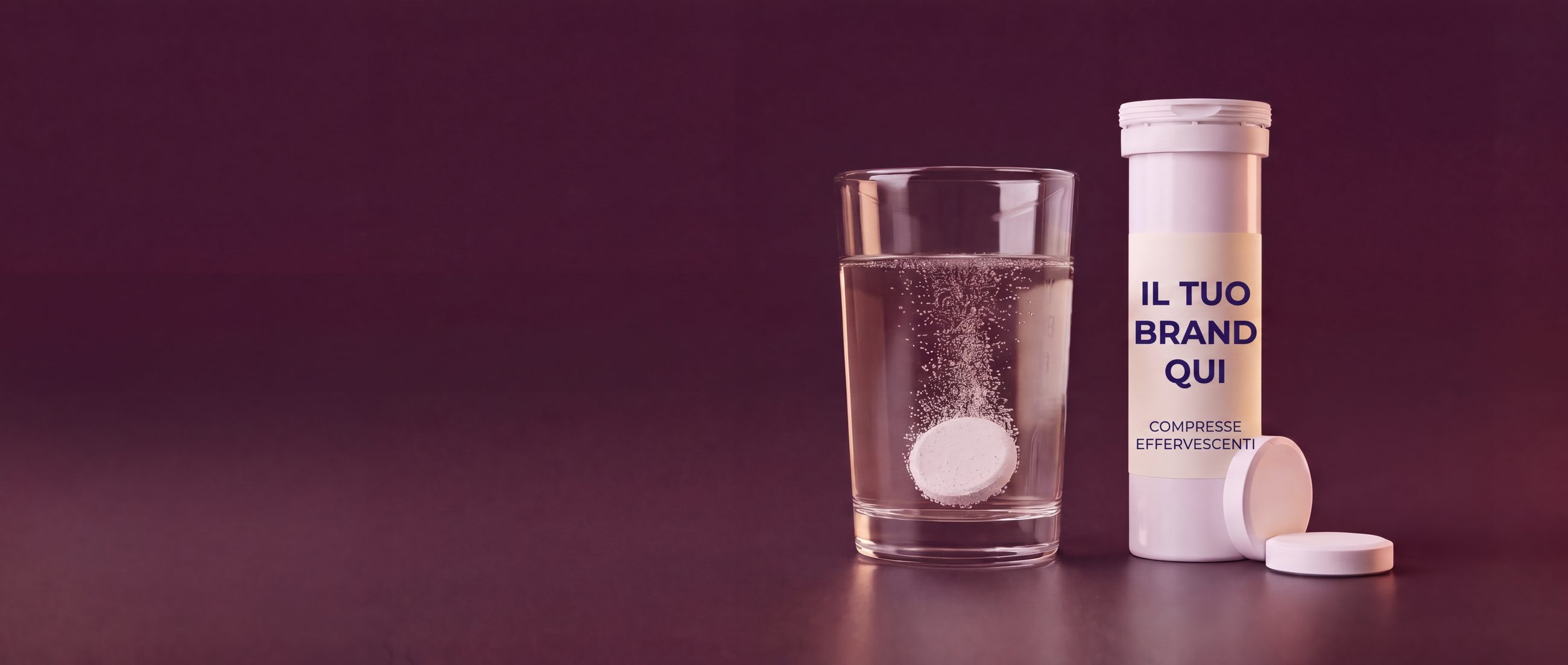 Tubo private label di compresse effervescenti con etichetta IL TUO BRAND QUI e una compressa che si dissolve in un bicchiere d'acqua