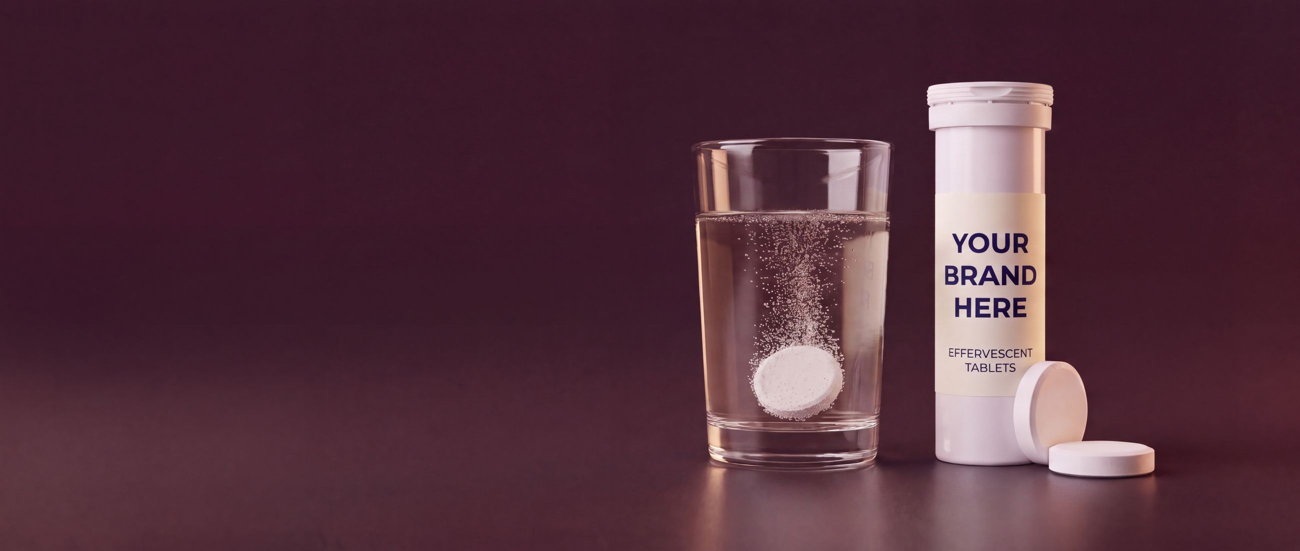 Private label effervescent tablet tube with a your-brand-here label and a tablet dissolving in a glass of water